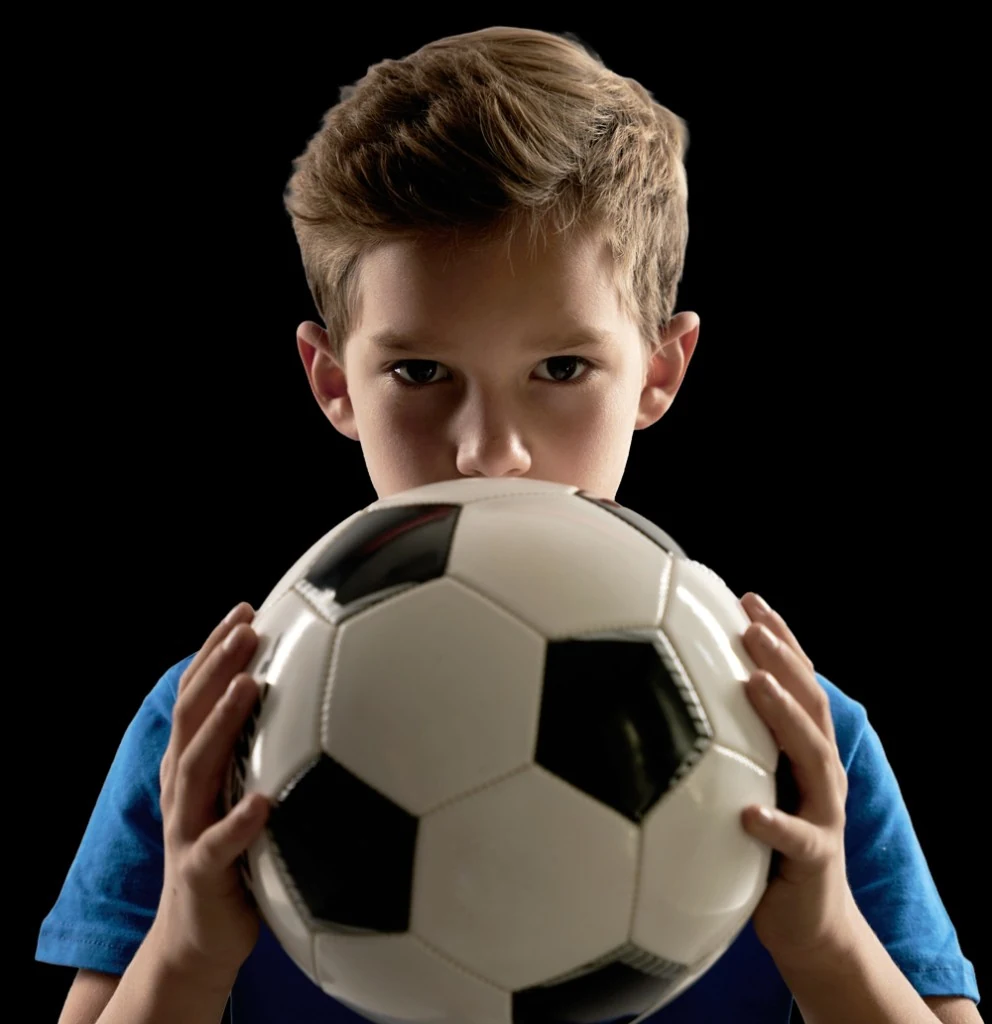 Menino atleta segurando uma bola de futebol